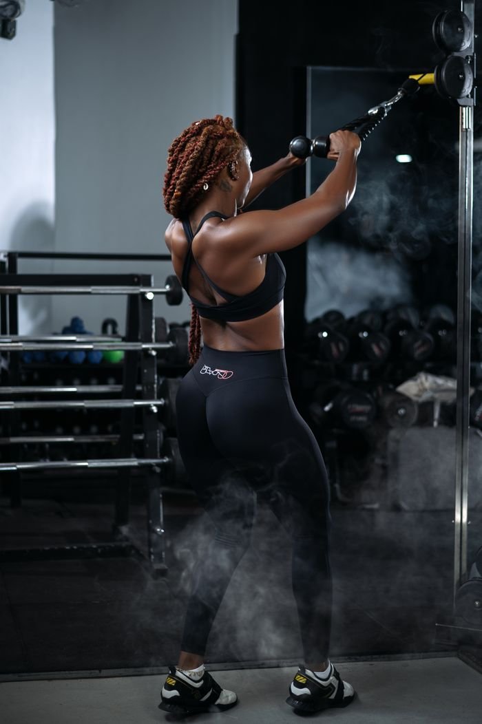 Services Focused woman exercising with cables at the gym, showcasing strength and determination.